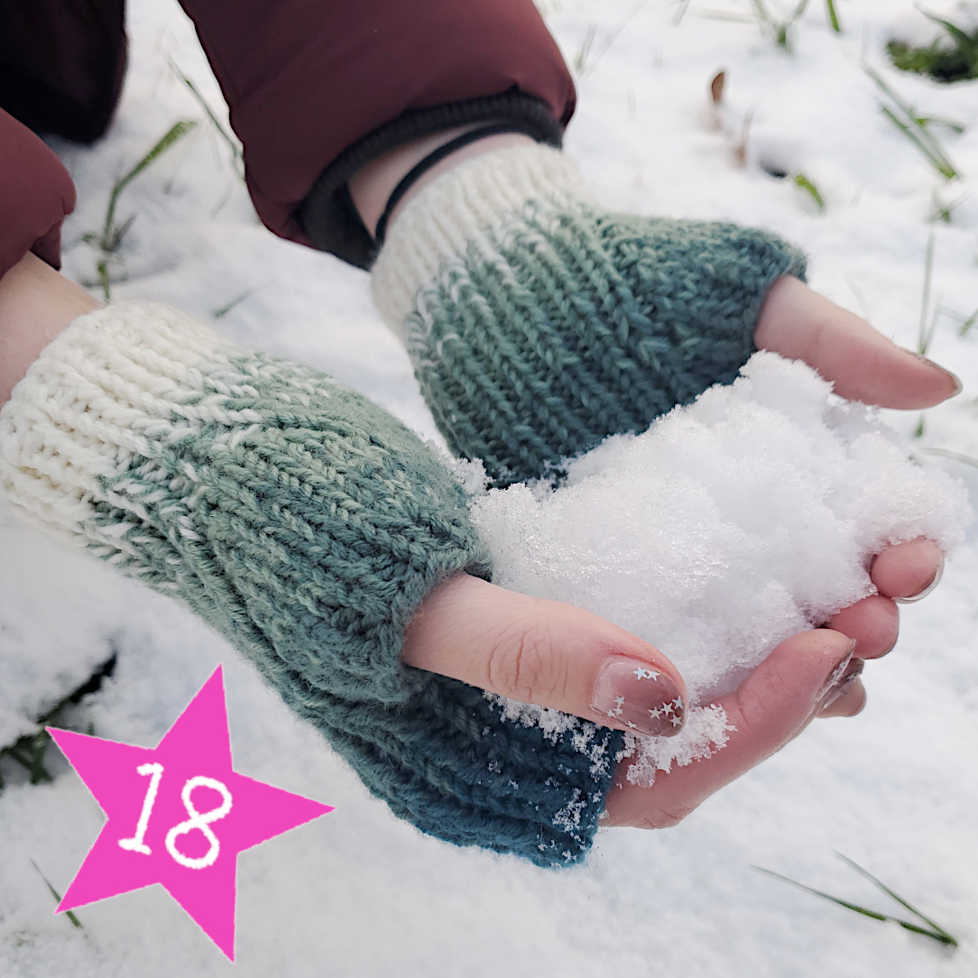 Zwei Hände im Schnee mit Handstulpen im Farbverlauf